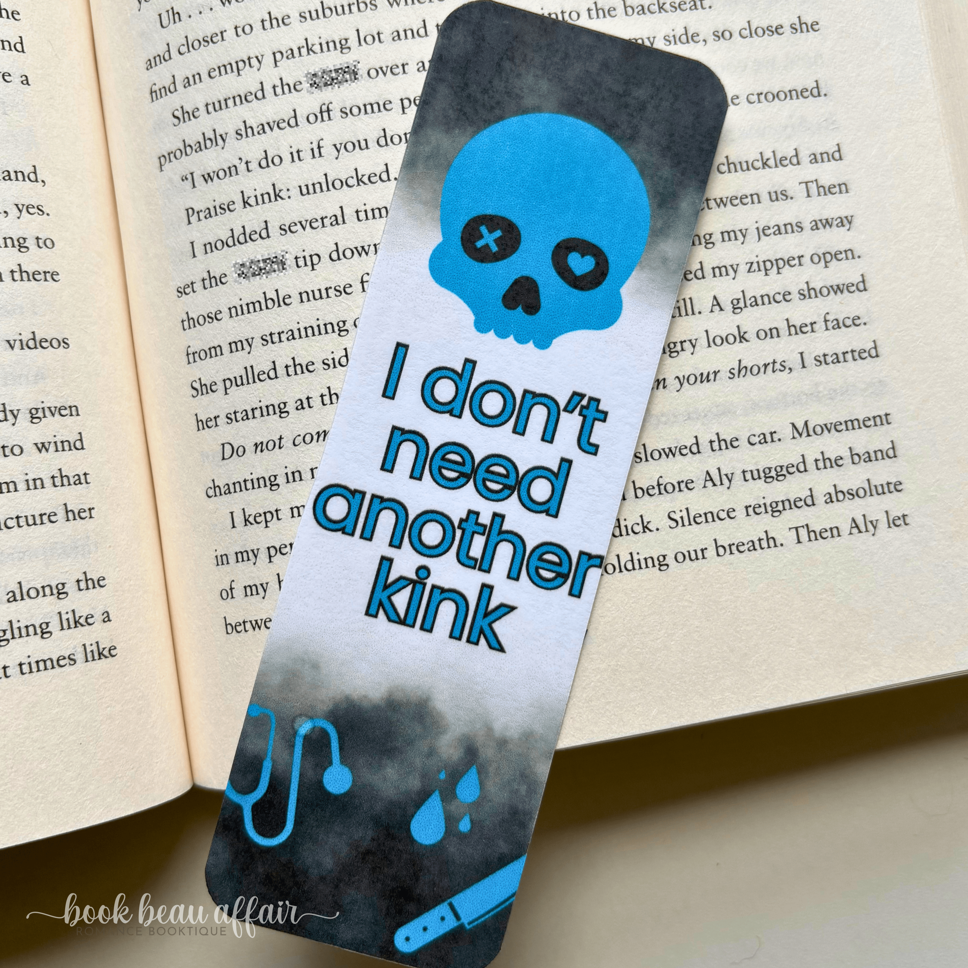 Bookmark with skull design and text on an open book. the text says I don't need another kink