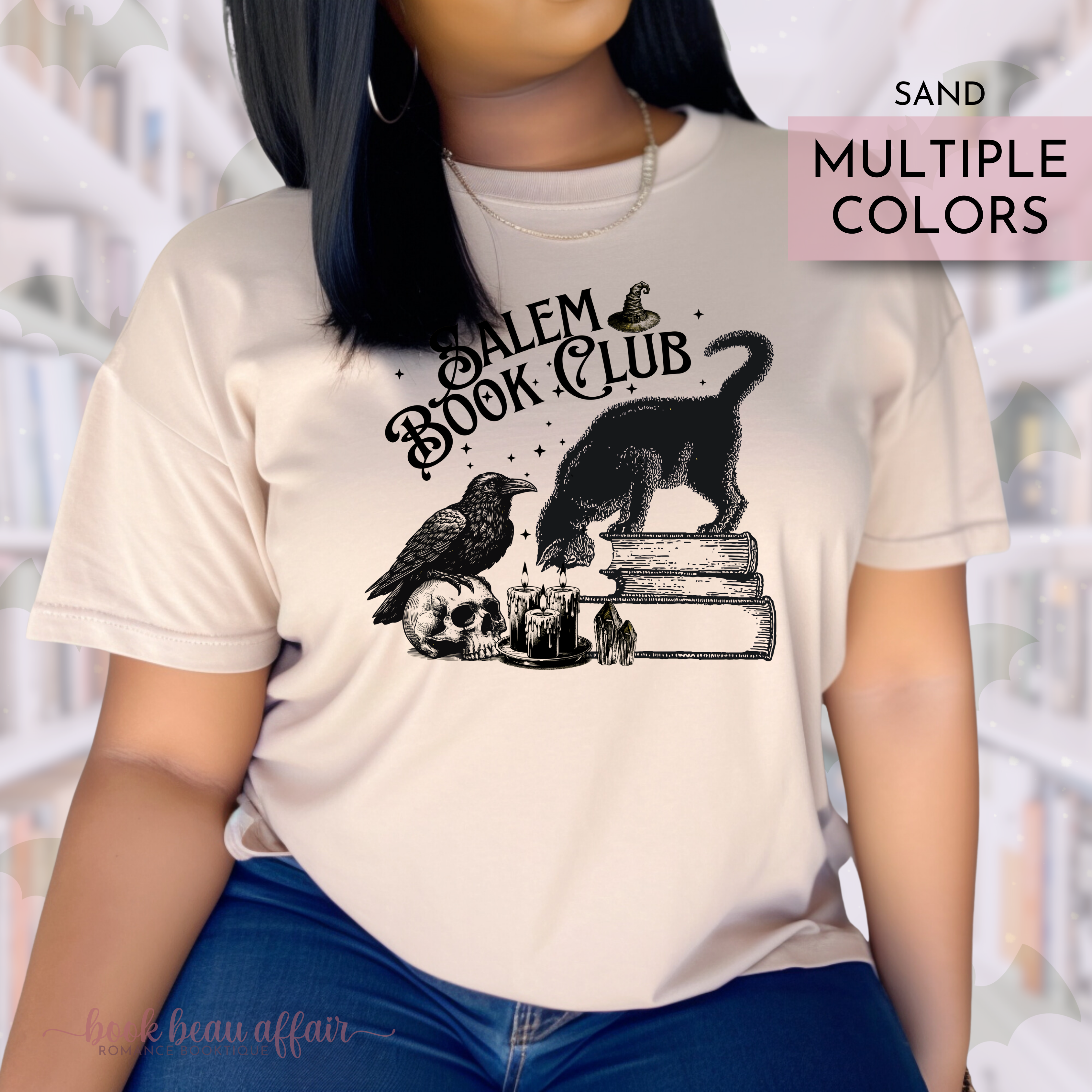 Person wearing a tan shirt that says Salem Book Club in text and has a black cat sitting on books