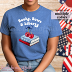 Person wearing a blue t-shirt with 'Books, Bows & Liberty' design in front of American flags.