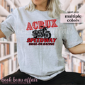 Person wearing a gray t-shirt with a motorcycle graphic and text, that says Acrux Speedway. Drag-on racing