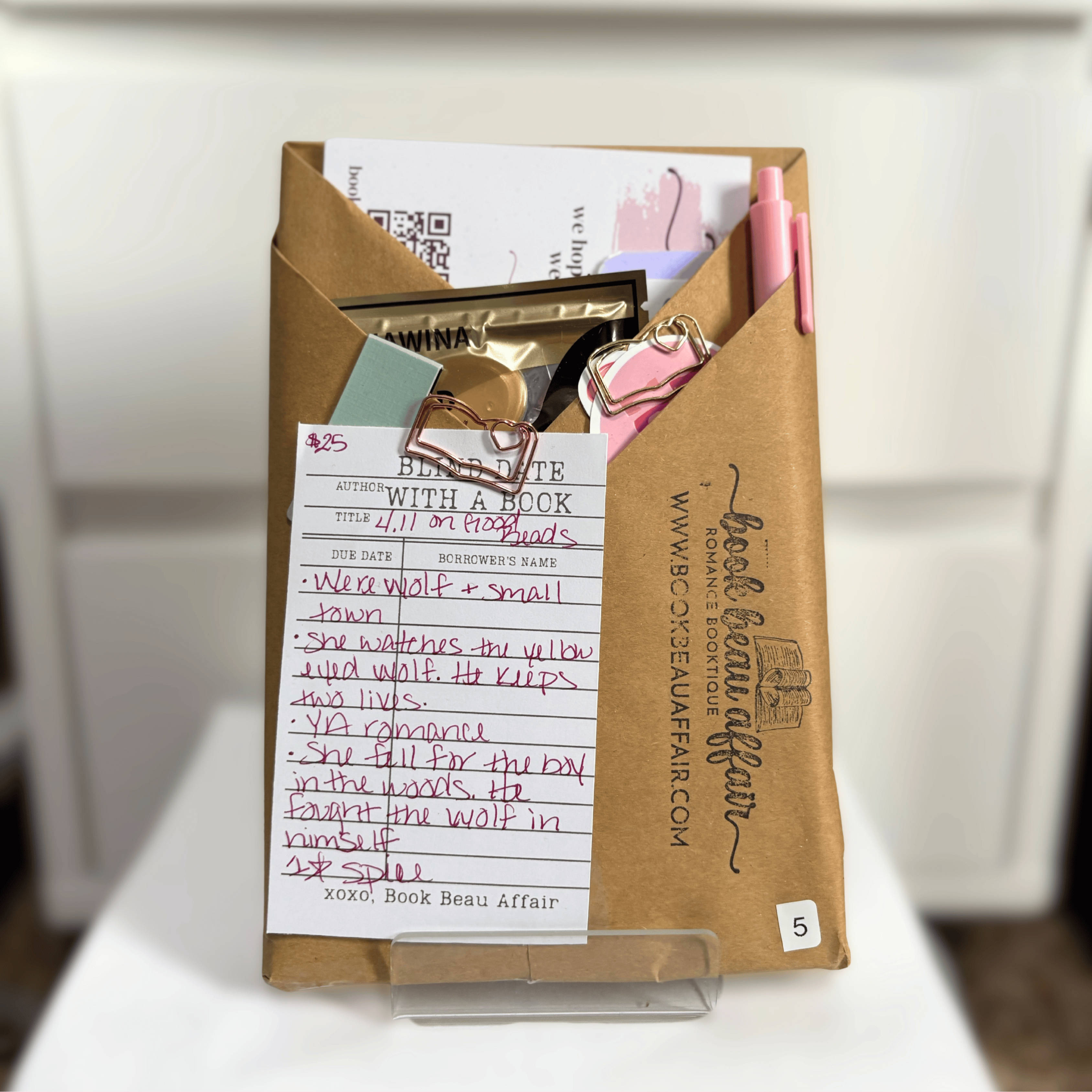 Blind Date with a Book. Mystery Book Wrapped in brown craft paper with a pen, stickers, bookmarks and other goodies