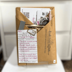 Blind Date with a Book. Mystery Book Wrapped in brown craft paper with a pen, stickers, bookmarks and other goodies