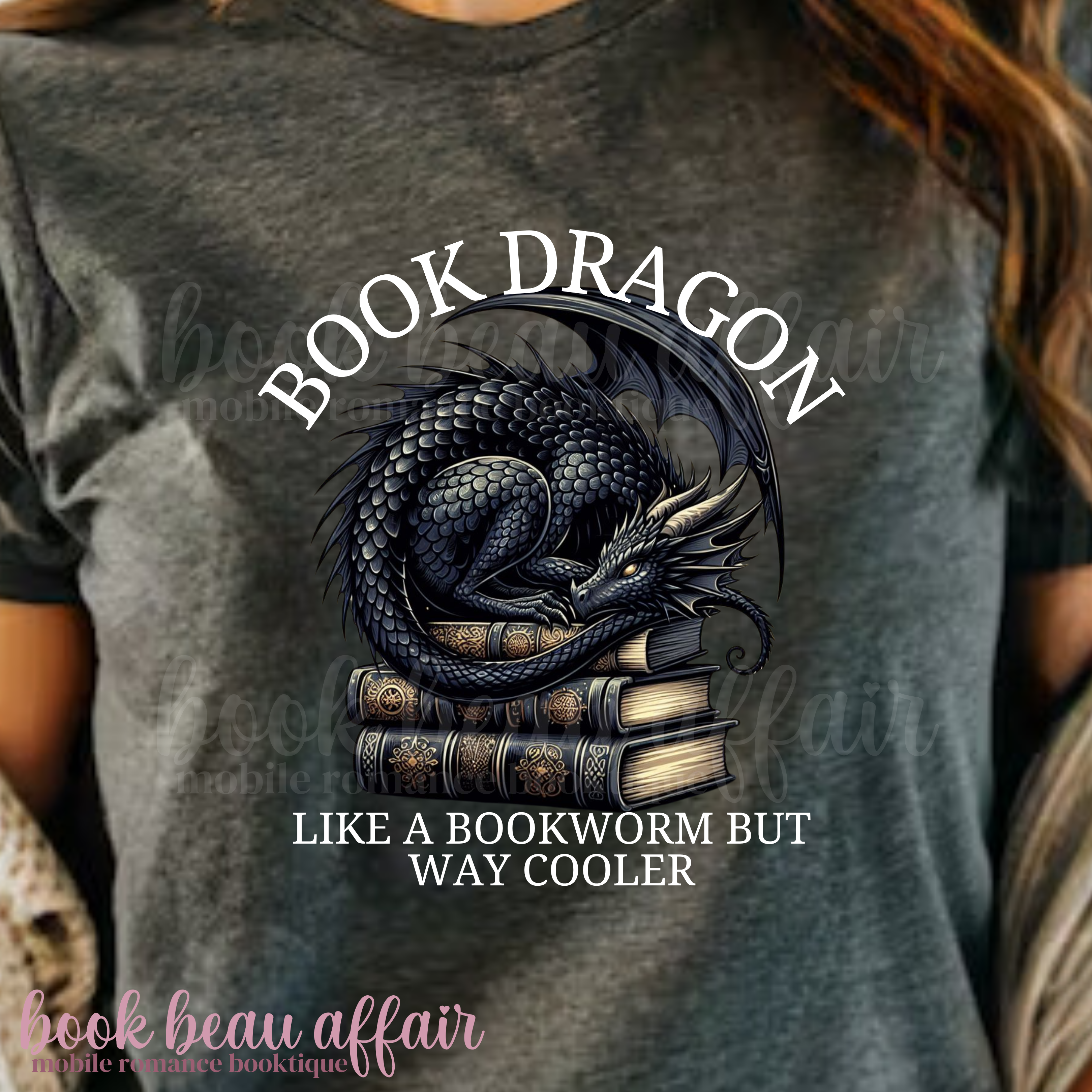 Gray t-shirt with a dragon laying on a stack of books and text that says book dragon, like a bookworm but way cooler