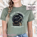 military green t-shirt with a dragon laying on a stack of books and text that says book dragon, like a bookworm but way cooler