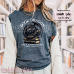 heather navy blue t-shirt with a dragon laying on a stack of books and text that says book dragon, like a bookworm but way cooler