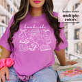 Person wearing a pink t-shirt with 'bookish' design and book related doodle icons in a library setting