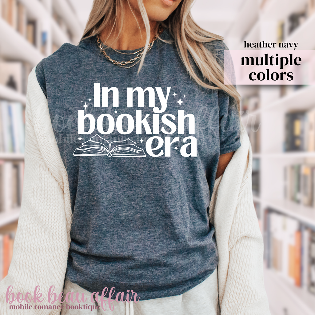 Person wearing a blue t-shirt with 'In my bookish era' text in a library setting