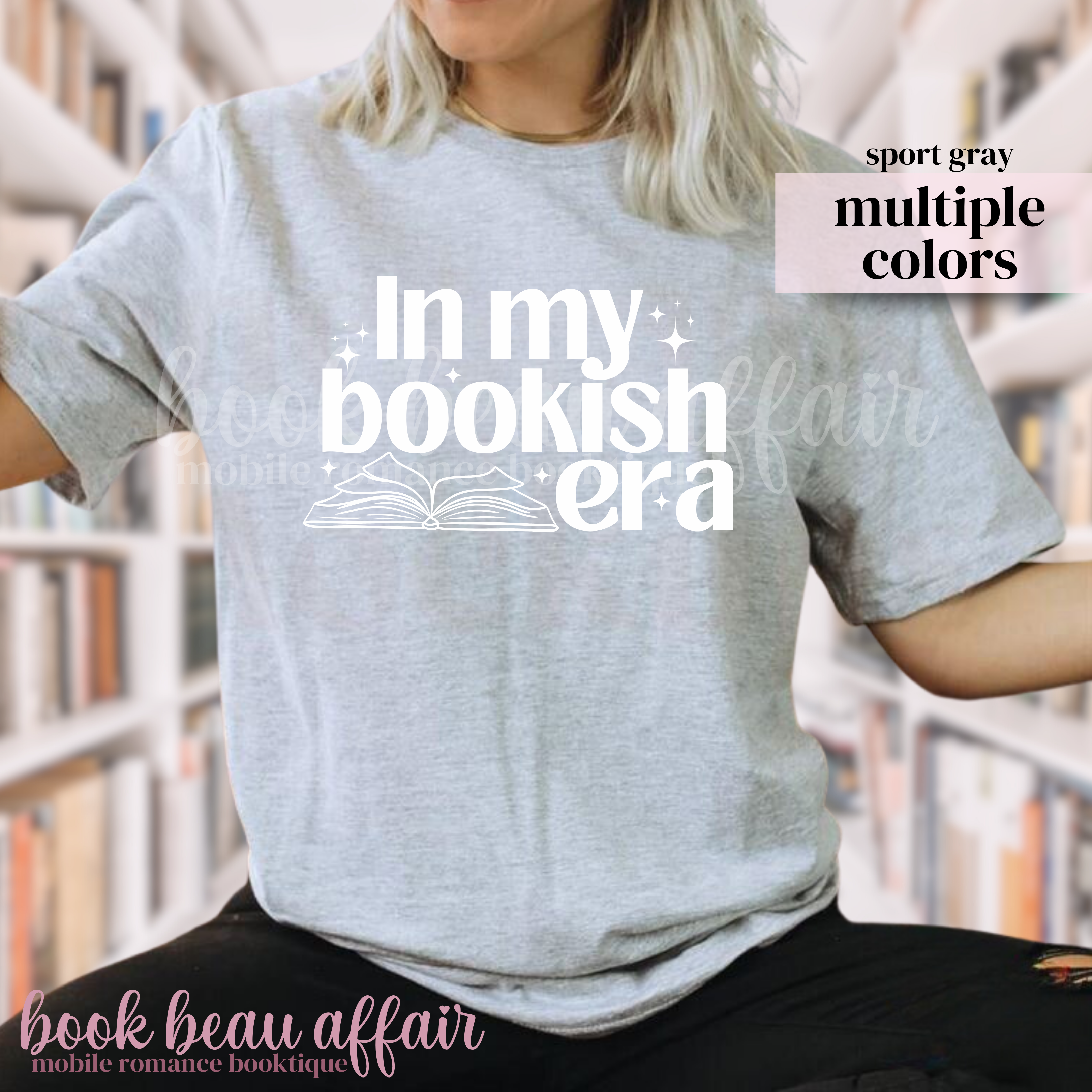Person wearing a gray t-shirt with 'In my bookish era' text, sitting in a library.
