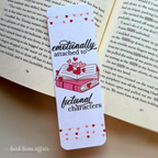 Bookmark with hearts and text 'emotionally attached to fictional characters' on an open book.