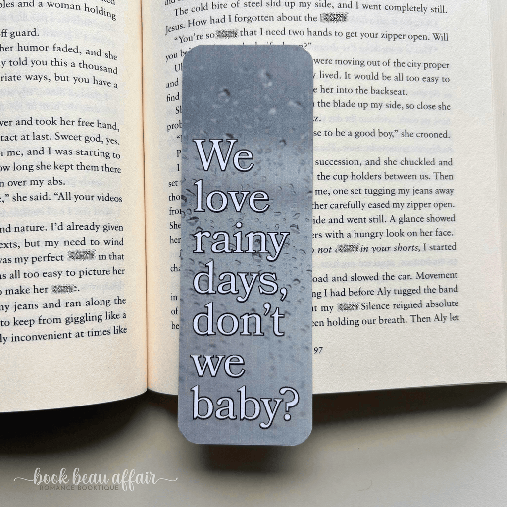 Bookmark with 'We love rainy days, don't we baby?' text on an open book
