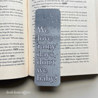 Bookmark with 'We love rainy days, don't we baby?' text on an open book