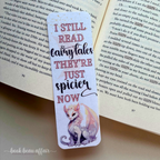 Bookmark with dragon illustration and text on an open book. The text says I still read fairytales they're just spicier now
