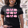 person wearing a black t-shirt with pink bows and pink stacks of books.