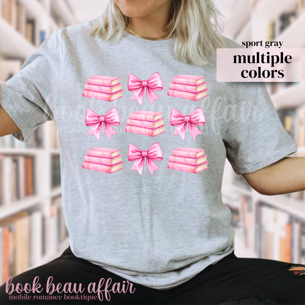 gray t-shirt with pink bows and pink stacks of books.