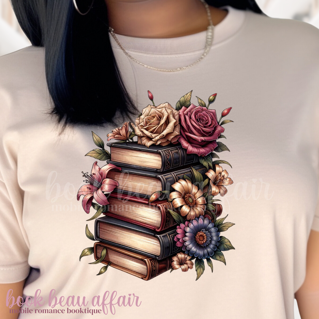 Beige t-shirt with a design of books and flowers on a person wearing it.