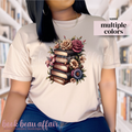 Beige t-shirt with a design of books and flowers on a person wearing it.