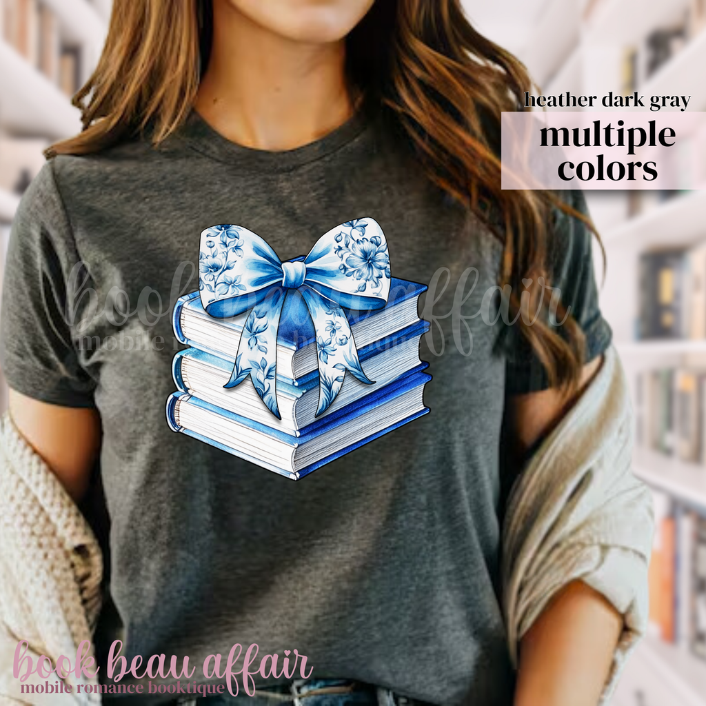 Stack of books with a blue floral bow on a dark gray t-shirt