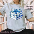 Stack of books with a blue floral bow on a gray t-shirt