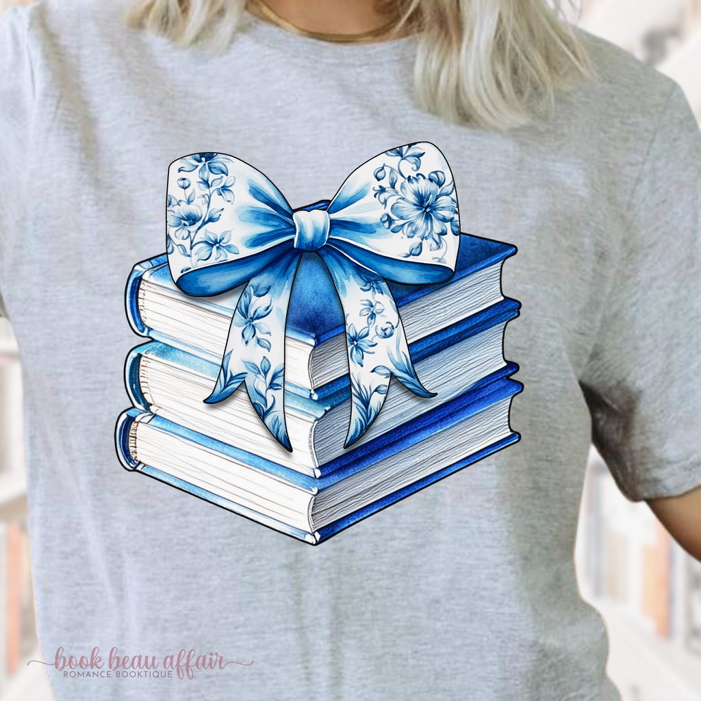 Close Up of watercolor stack of books and chinoiserie floral bow on top. coquette-style bow. soft bookish tee. Sport Gray
