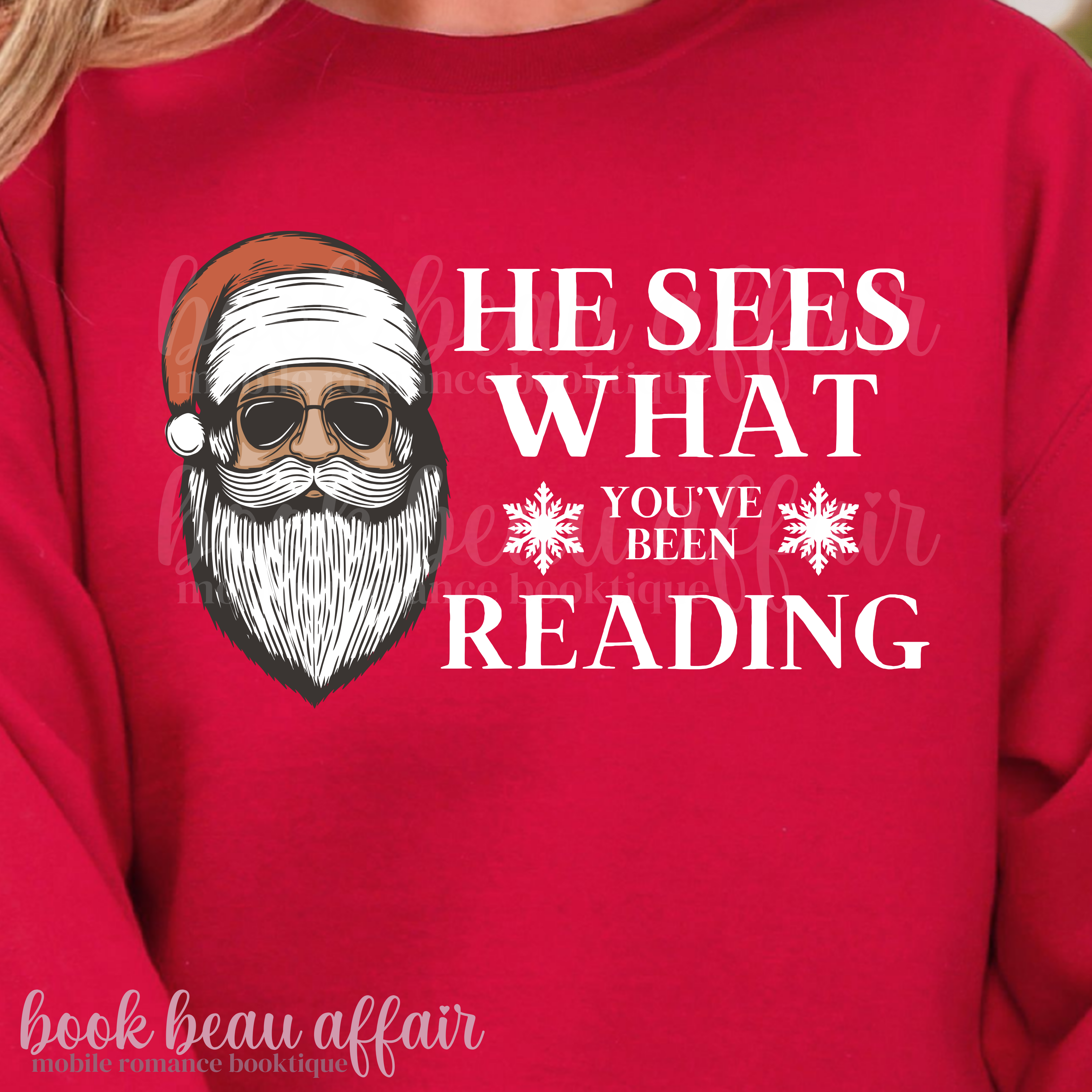 Red sweatshirt with a graphic of Santa Claus and text 'He sees what you've been reading' 