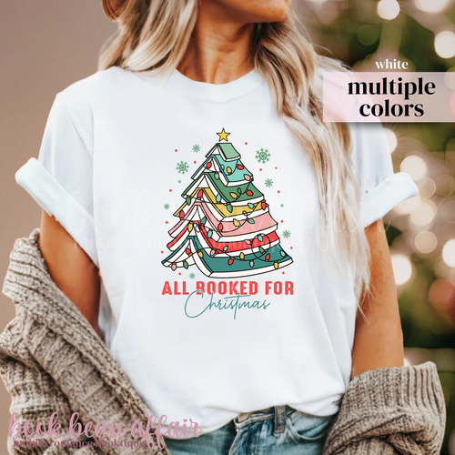 white t-shirt with text All Booked For Christmas with a Christmas Tree Made out of books