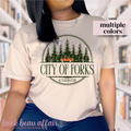 Person wearing a white t-shirt with 'City of Forks, Washington' with an orange truck and trees in the background