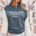 Person wearing a blue t-shirt with 'I closed my book to be here' text in a library setting.