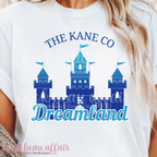 White t-shirt with blue castle design and text 'The Kane Co Dreamland' worn by a person.