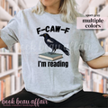 Gray t-shirt with a crow on a book graphic and text 'F-CAW-F I'm reading' 