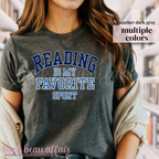 Person wearing a gray t-shirt with 'Reading is my favorite sport' text, standing in a bookstore.