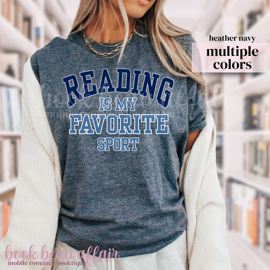 Person wearing a blue t-shirt with 'Reading is my favorite sport' text in a library setting.