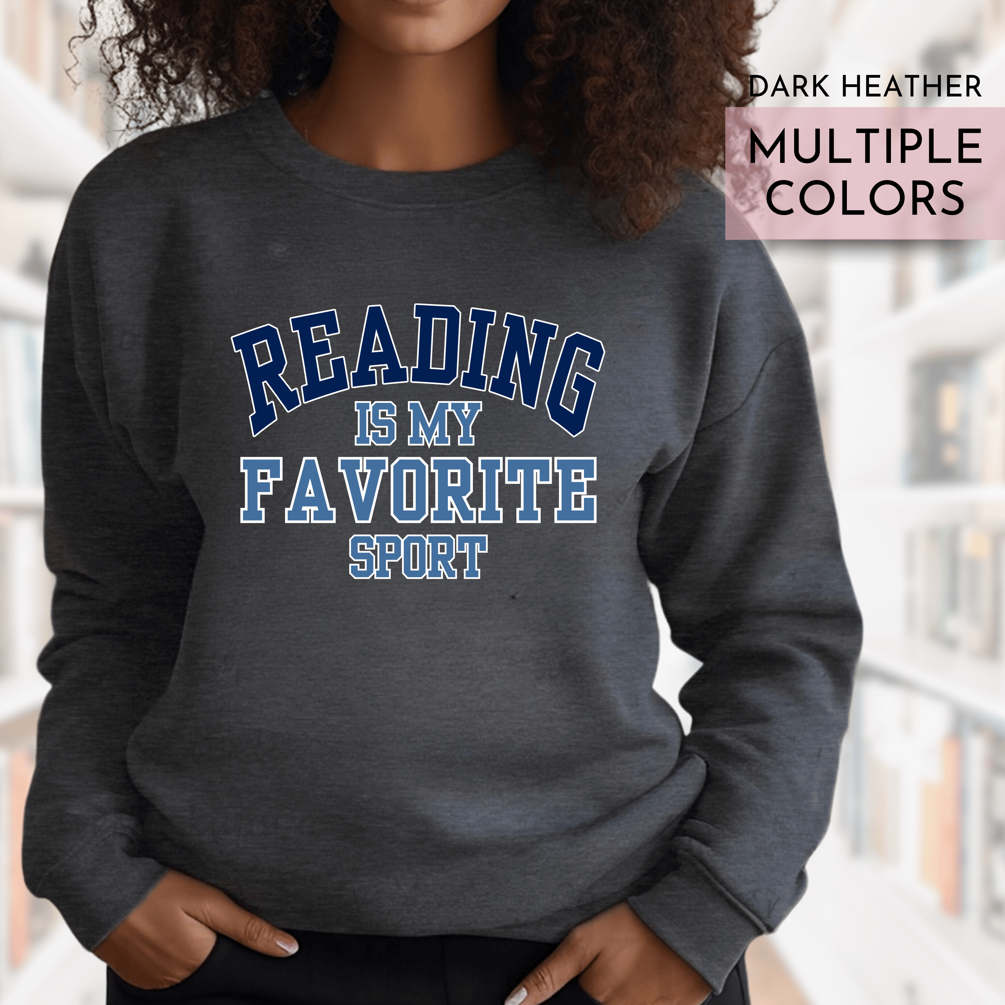 Person wearing a dark heather sweatshirt with 'Reading is my favorite sport' text in a library setting.
