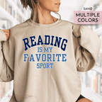 Beige sweatshirt with 'Reading is my favorite sport' text worn by a person, with blurred background.