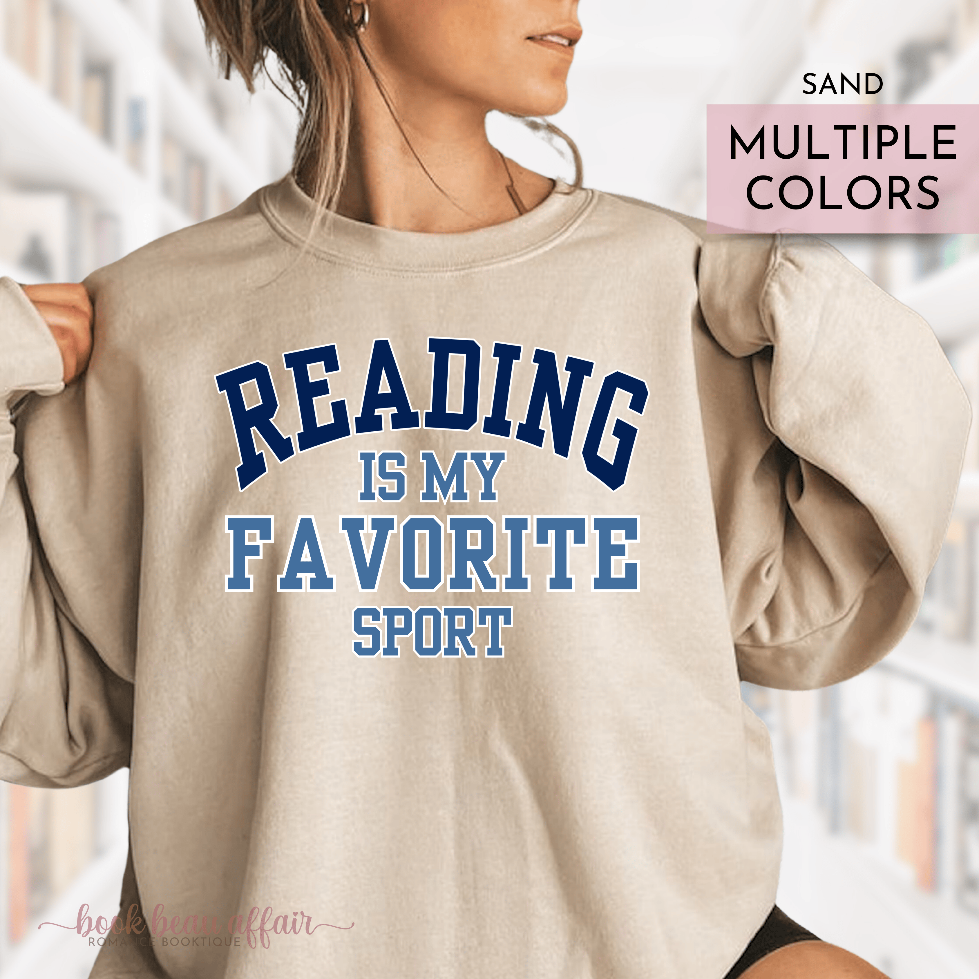 Beige sweatshirt with 'Reading is my favorite sport' text worn by a person, with blurred background.