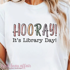 White t-shirt with 'HOORAY! It's Library Day!' text worn by a person.