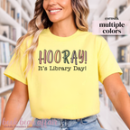 Yellow t-shirt with 'HOORAY! It's Library Day!' text worn by a person.