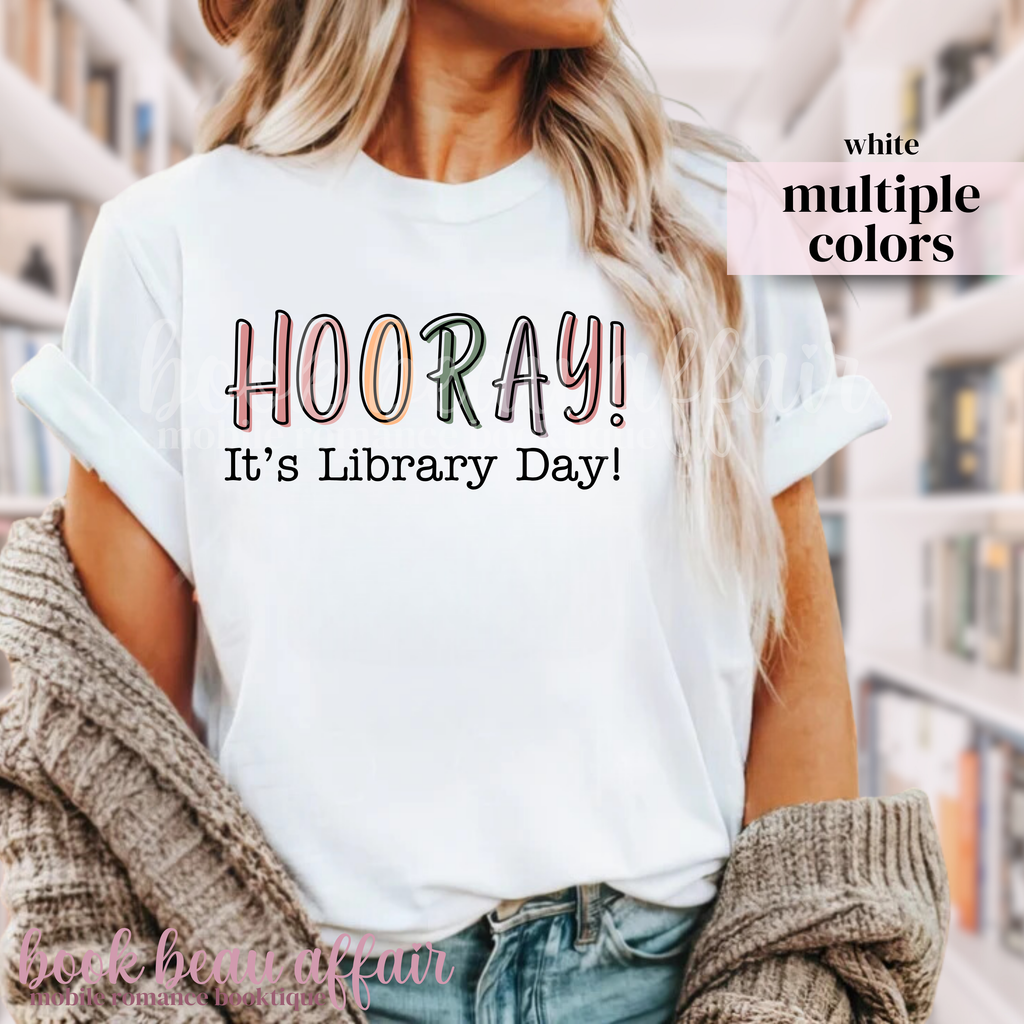 White t-shirt with 'HOORAY! It's Library Day!' text worn by a person.