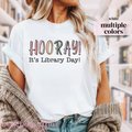 White t-shirt with 'HOORAY! It's Library Day!' text worn by a person.
