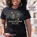 Person wearing a black t-shirt with 'House of Wind book club' design in a library setting