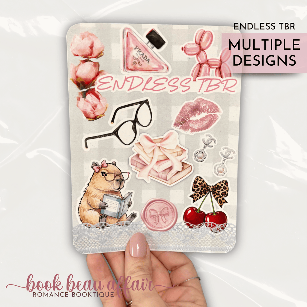Romance themed kindle case insert that says "endless tbr" with Chanel earrings and a bottle of Prada perfume