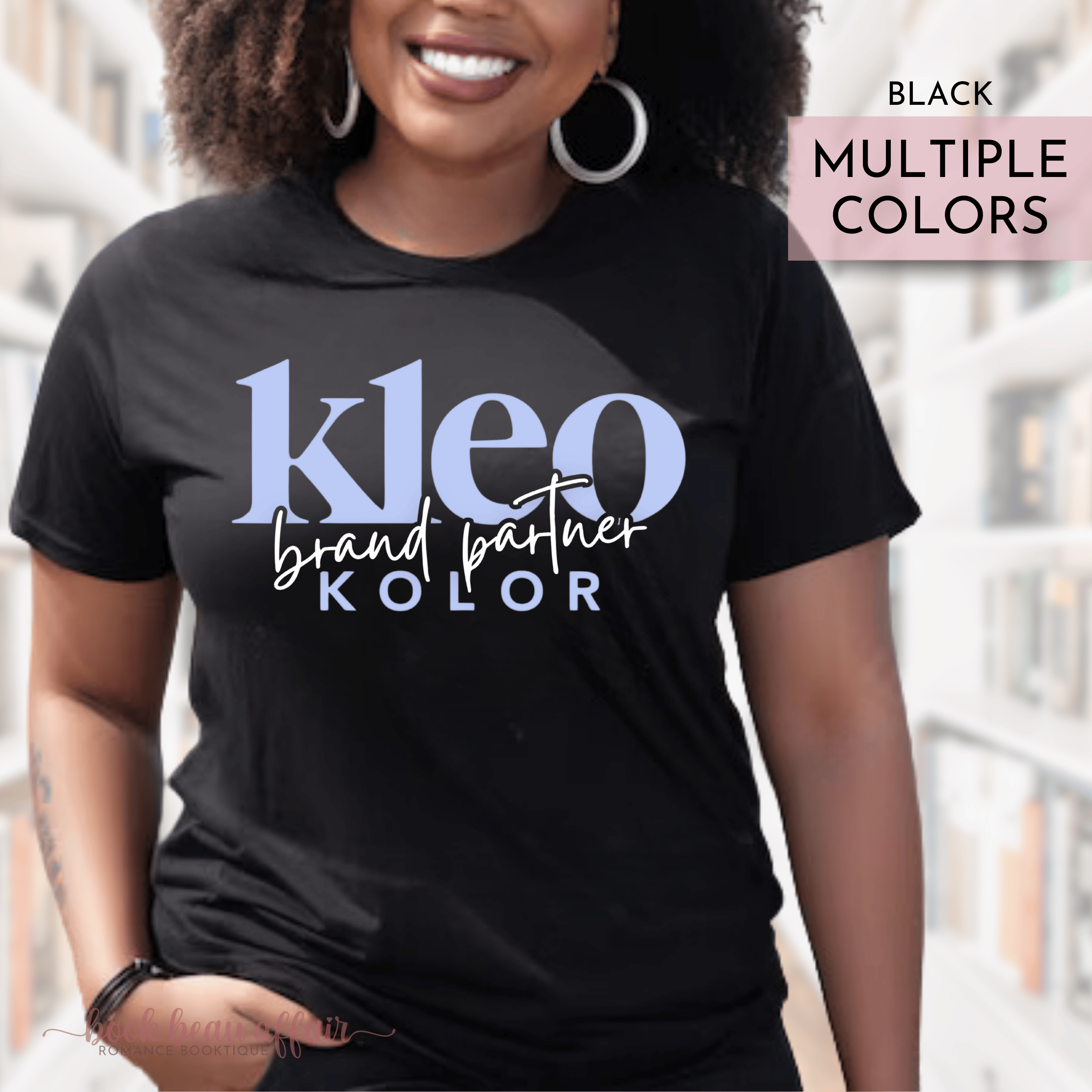 Person wearing a black t-shirt with 'Kleo Kolor Brand Partner' text, standing in an urban setting.