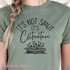 Person wearing a green t-shirt with 'It's Not Smut, It's Cliterature' text and book graphic.