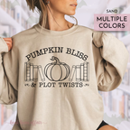 Beige sweatshirt with 'Pumpkin Bliss & Plot Twists' text and pumpkin graphic, worn by a person.