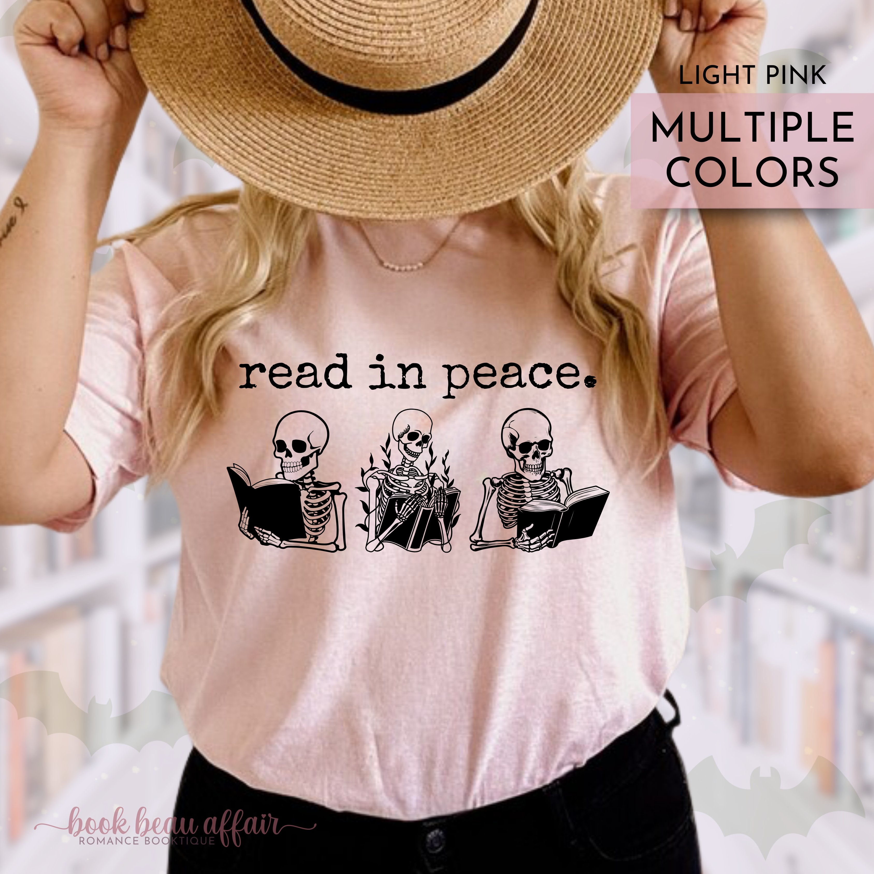 Person wearing a light pink t-shirt with skeleton graphics and text that says read in peace, holding a straw hat.