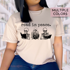 Person wearing a t-shirt with skeleton illustrations and 'read in peace' text, set against a blurred library background.