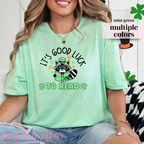 St. Patricks Day Themed Shirt. Illustration of a raccoon holding a green book with text that says "It's Good Luck to Read"