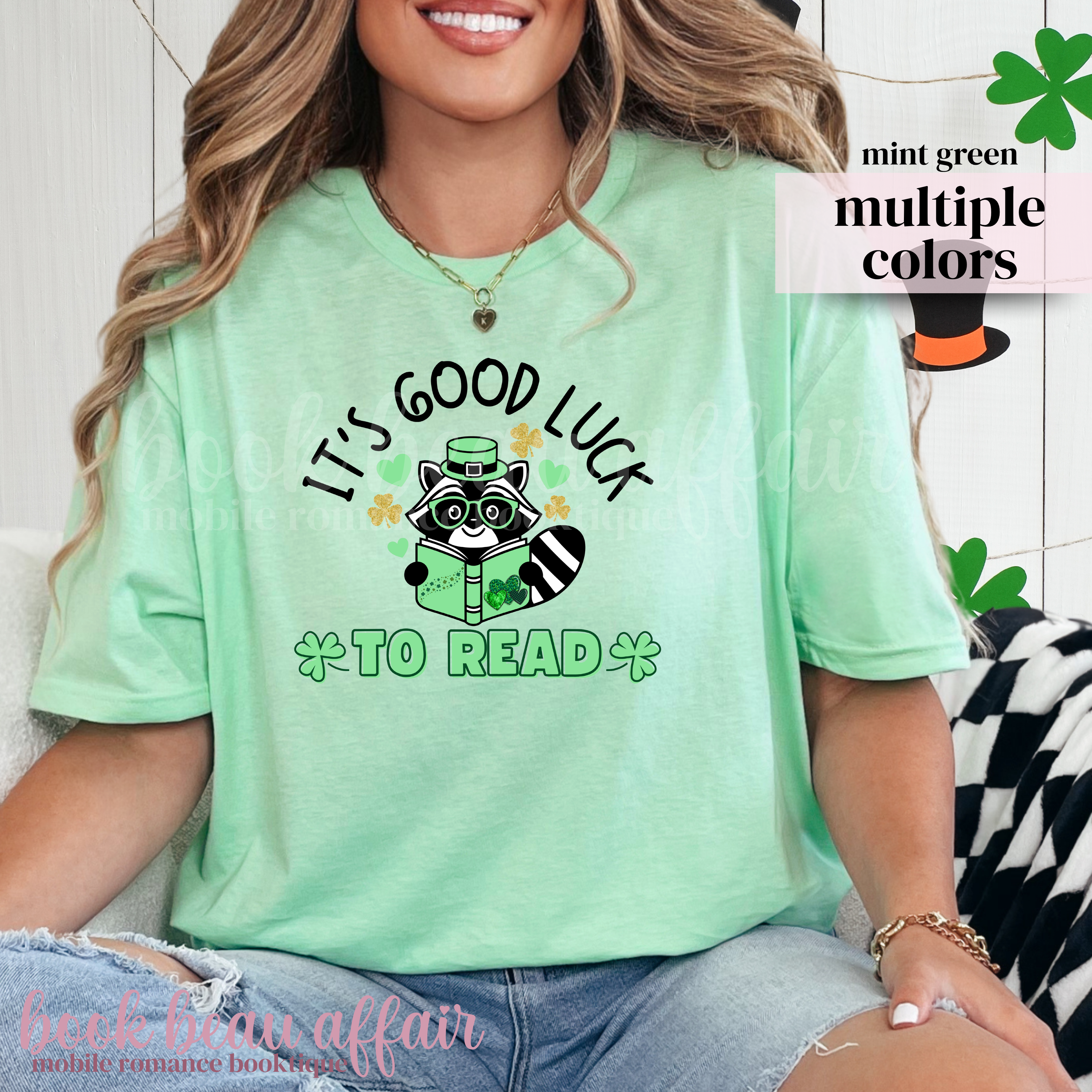 St. Patricks Day Themed Shirt. Illustration of a raccoon holding a green book with text that says "It's Good Luck to Read"