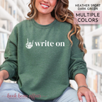 Person wearing a green sweatshirt with 'write on' text and rock on hand symbol